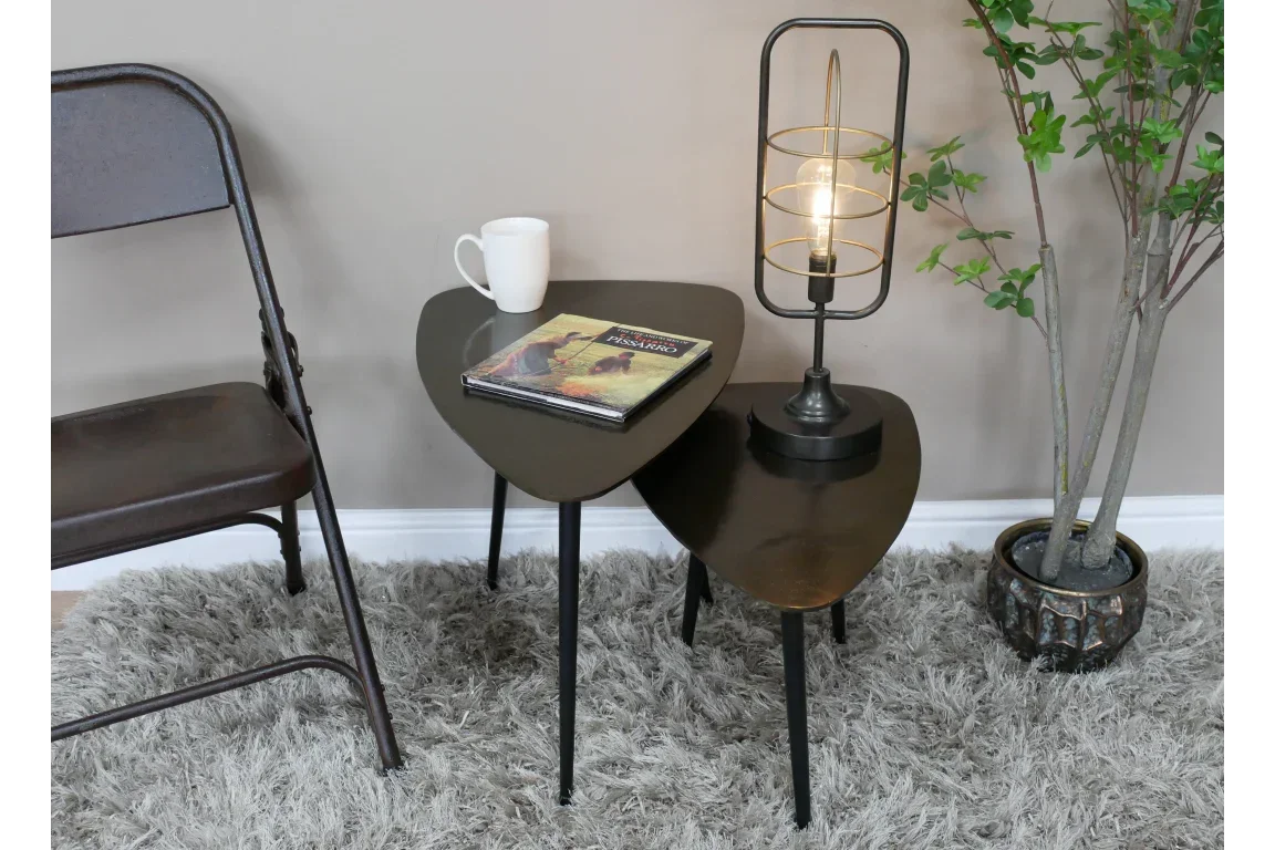 Set of two dark wood nesting tables with black legs, lamp, mug, and book on shaggy rug
