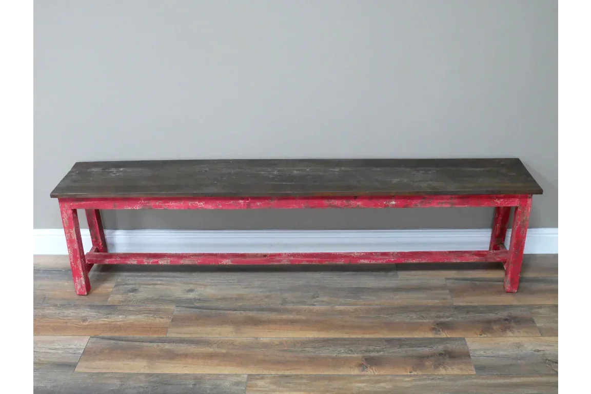 Vintage wooden bench with distressed red frame and dark top on wood floor