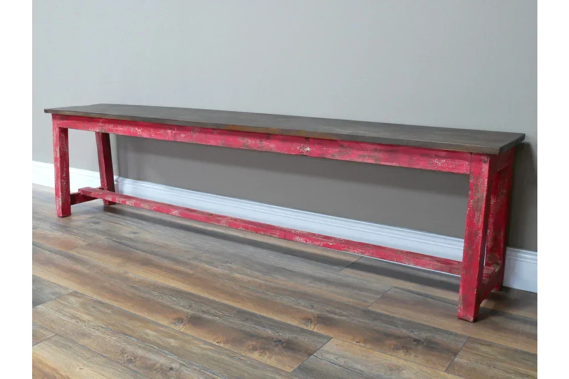Rustic wooden bench with distressed red frame and dark wood seat on laminate flooring