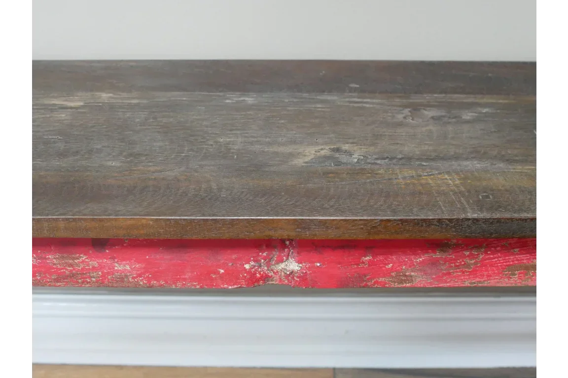 Close-up of rustic wooden table top with distressed red trim detail