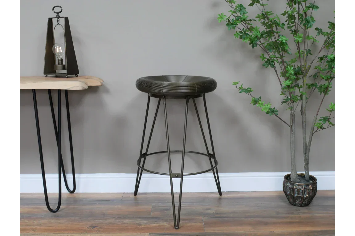 Industrial metal bar stool with hairpin legs and round seat next to wooden side table