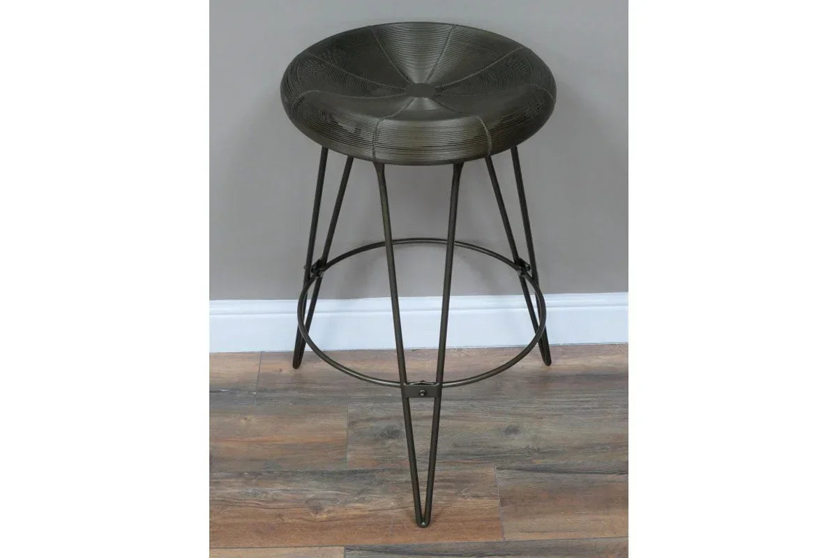 Black metal bar stool with round seat and tripod legs on wood flooring