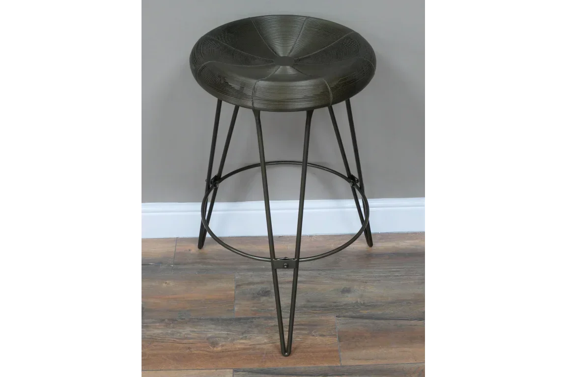 Black metal bar stool with round seat and tripod legs on wood floor
