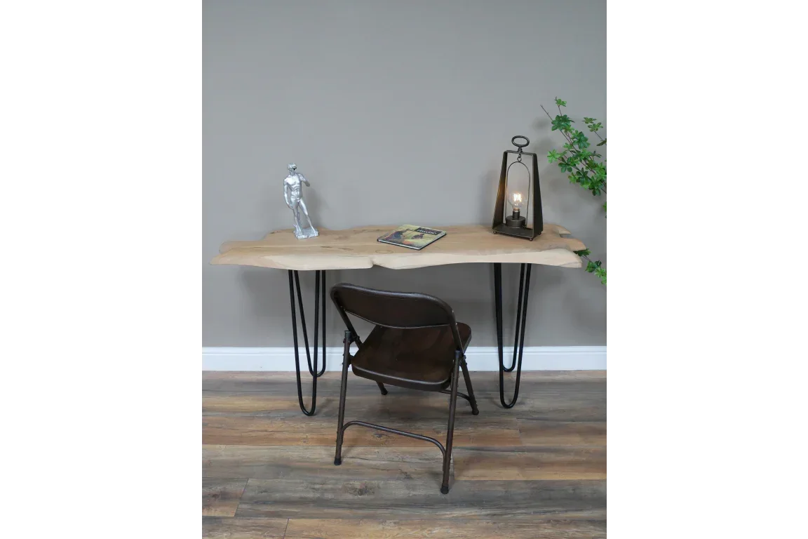 Live edge wood desk with black hairpin legs and brown metal chair on wood floor