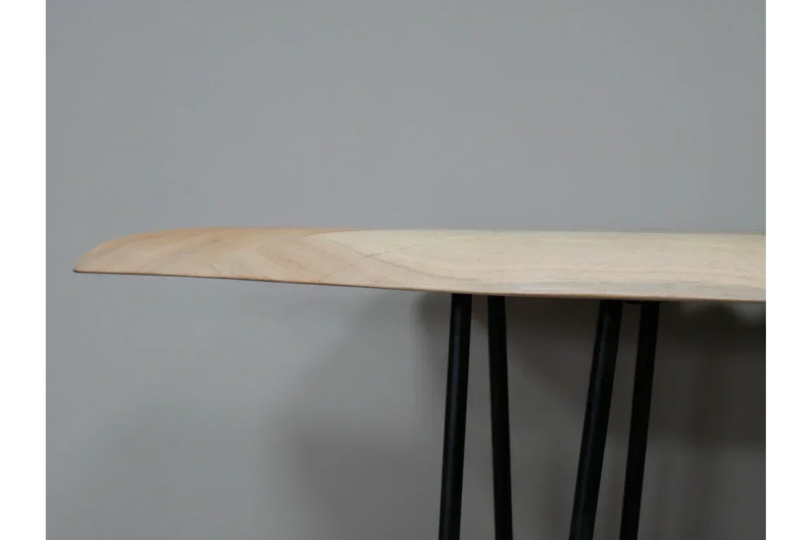 Close side view of wooden dining table with hairpin metal legs against grey wall