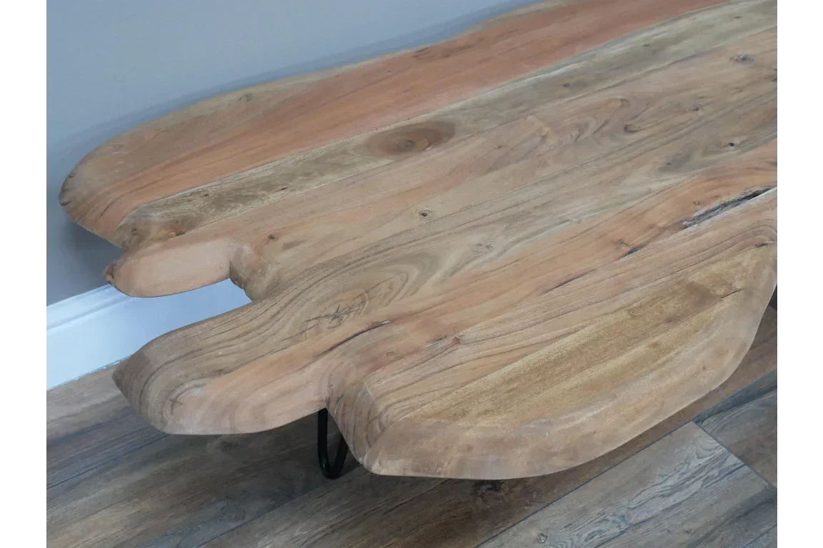 Live edge wooden coffee table with natural grain and curved edges on wood floor