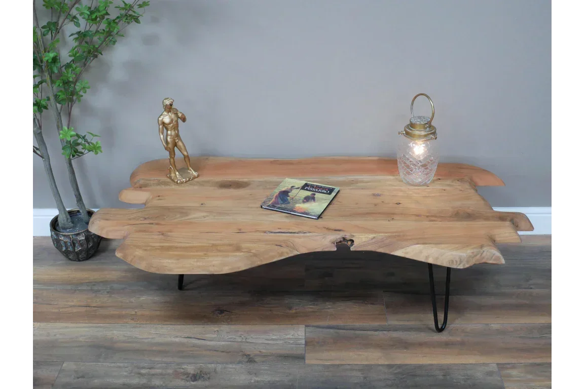 Live edge wooden coffee table with metal legs, decor, and book on wood floor