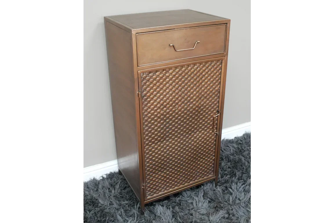 Bronze metal cabinet with woven textured door and single top drawer on grey rug