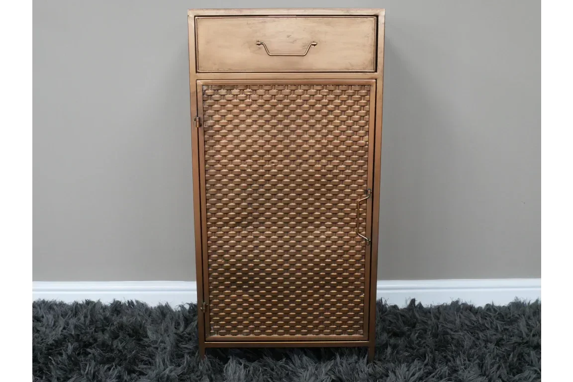 Bronze metal storage cabinet with patterned door and single top drawer on grey rug