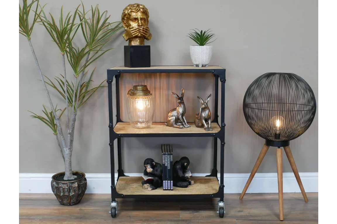 Industrial shelving unit with wooden shelves, decorative ornaments, and modern tripod lamp