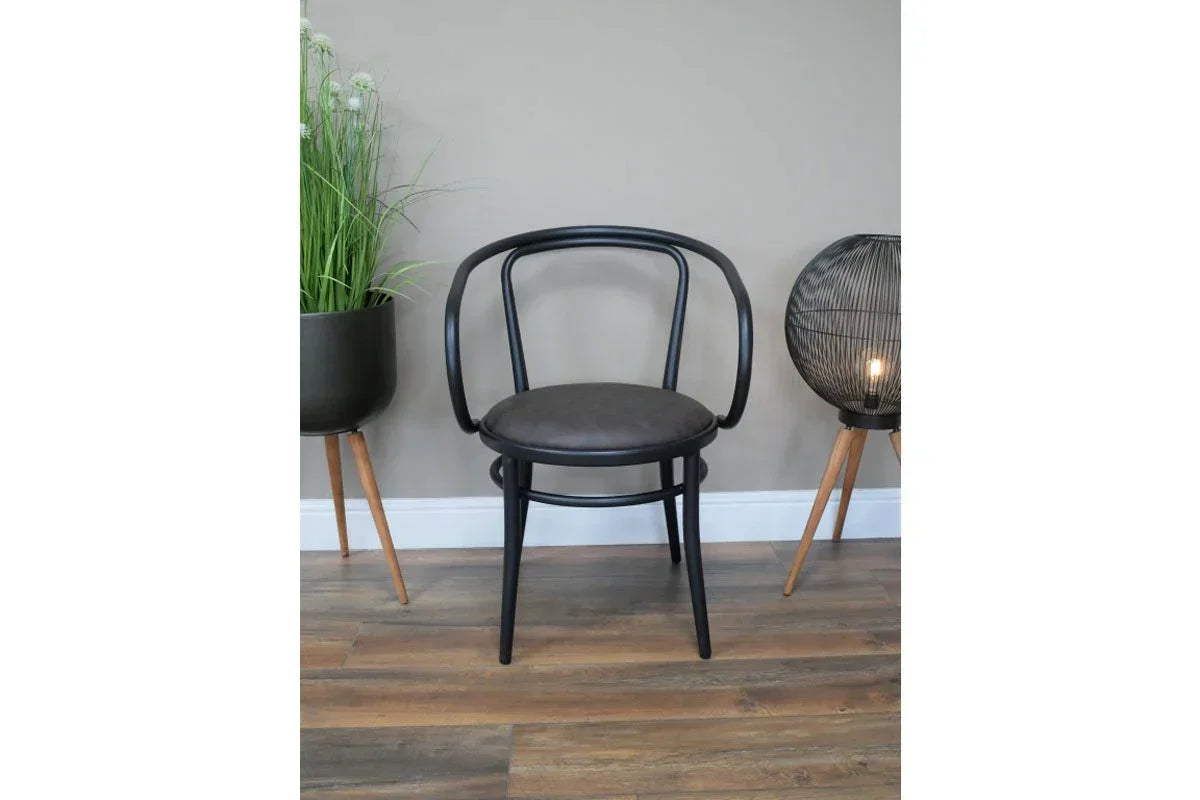 Black dining chair with curved backrest and round seat on wood floor, modern decor