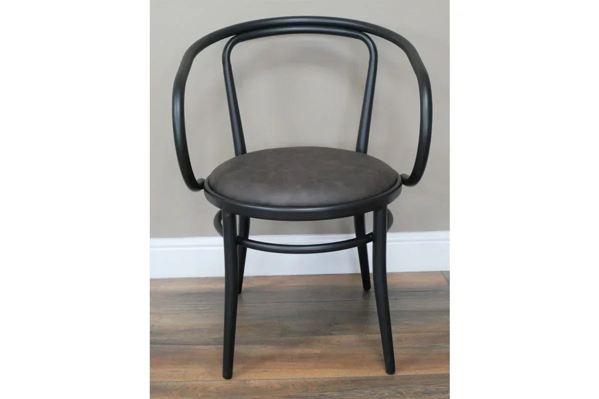 Curved black dining chair with round upholstered seat on wooden floor