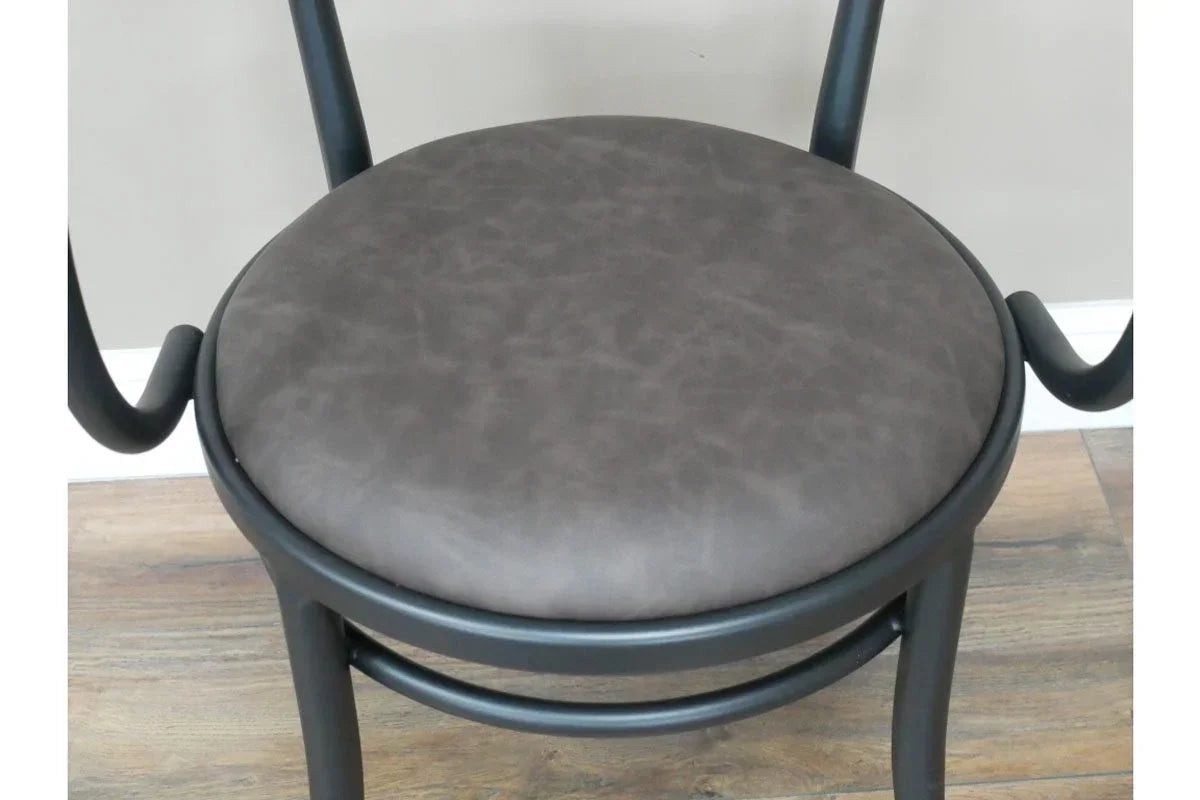 Round dining chair with dark faux leather seat and black curved frame on wood floor