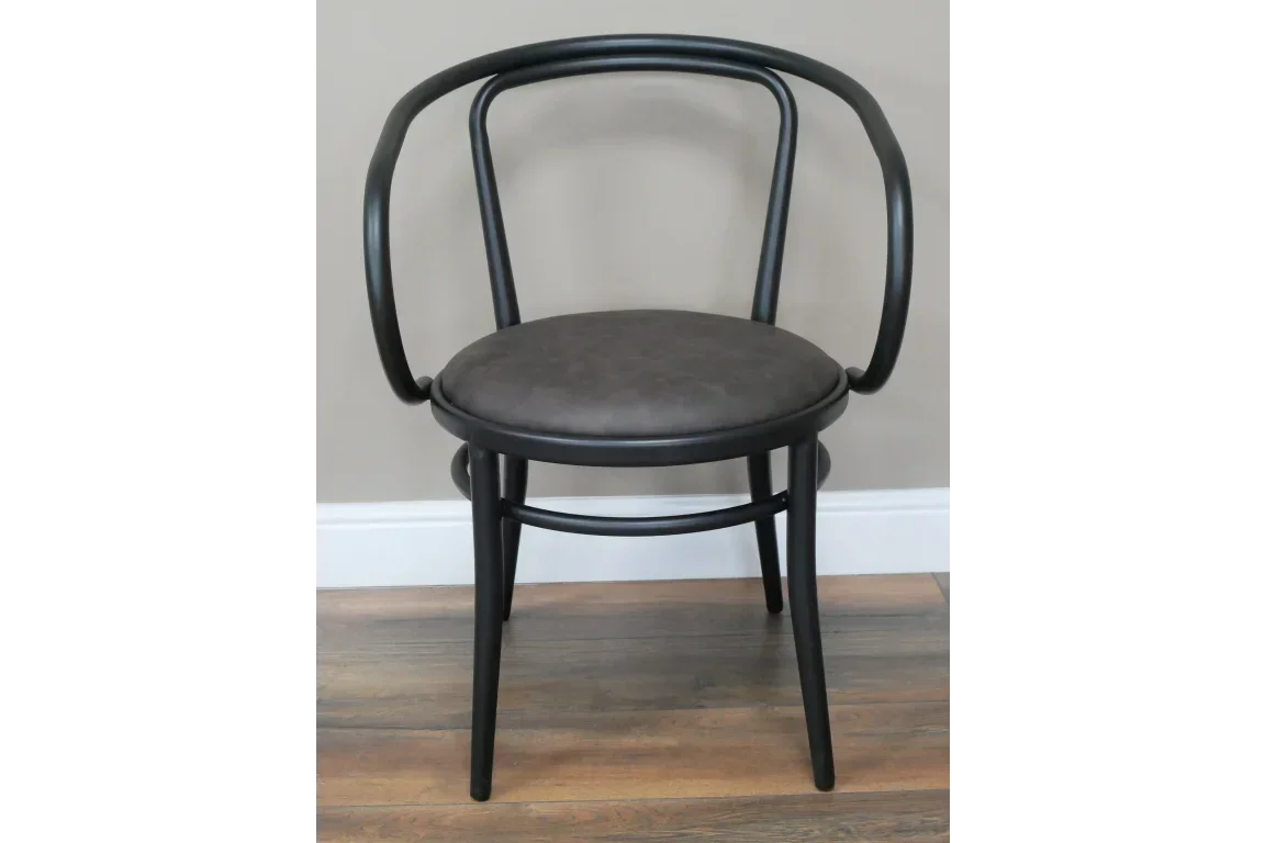 Black bentwood chair with curved backrest and round cushioned seat on wooden floor