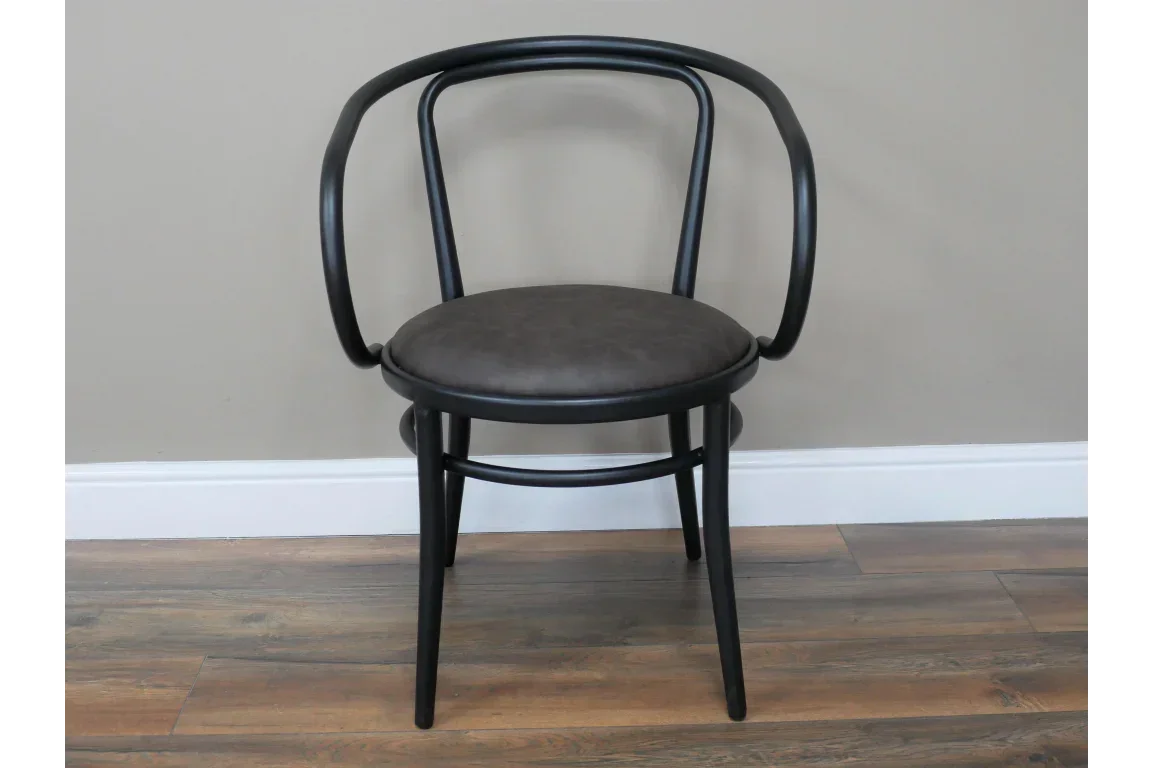 Black bentwood dining chair with curved back and round padded seat on wooden floor