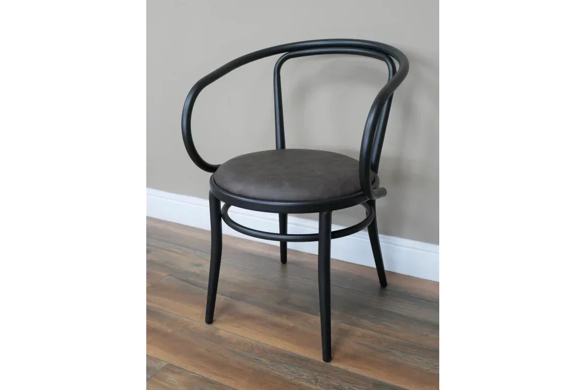 Black bentwood dining chair with curved back and brown padded seat on wooden floor