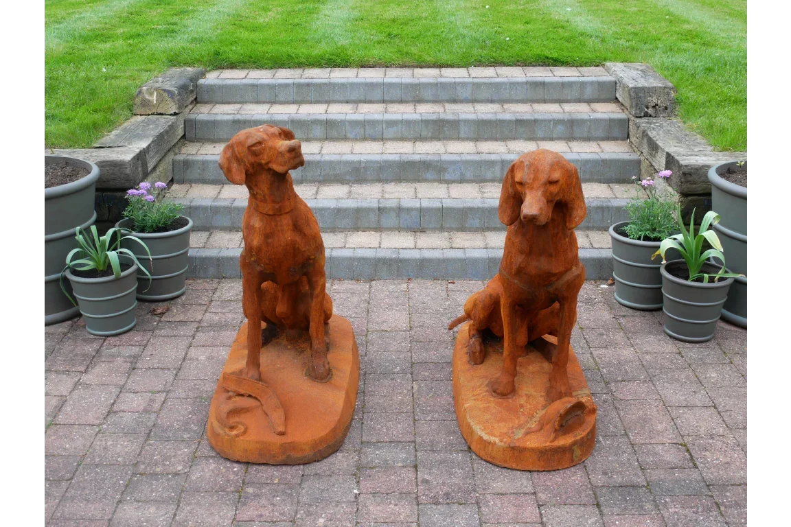 Rust effect dog garden ornaments on patio with potted plants and stone steps in background