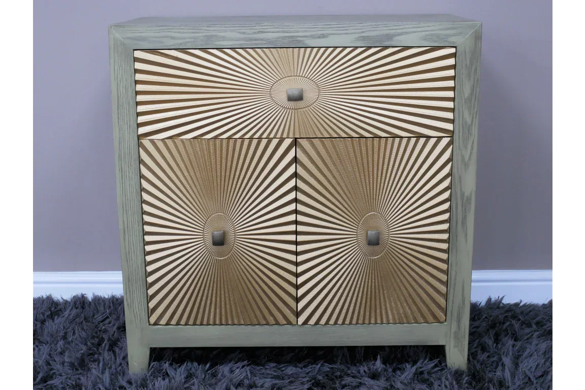 Gold sunburst pattern cabinet with two doors and drawer on grey rug