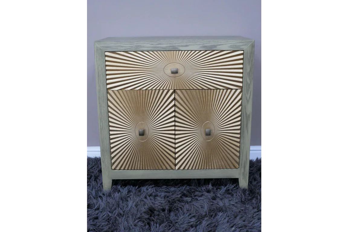 Wooden chest of drawers with geometric sunburst pattern and square handles on grey rug