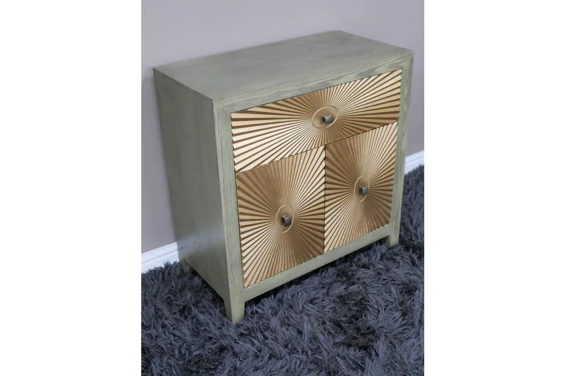 Three drawer wooden chest with gold sunburst pattern fronts on gray carpet
