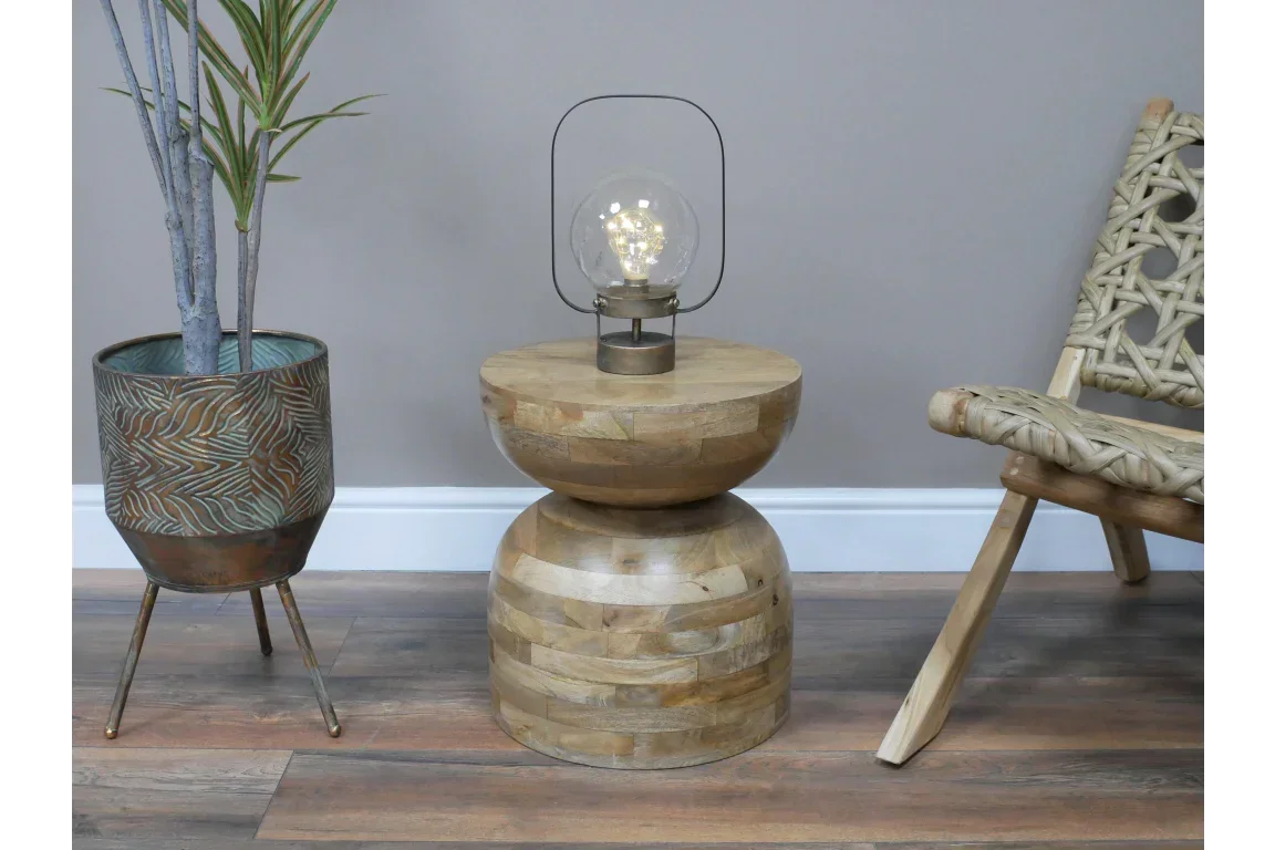 Round mango wood side table with natural finish, modern lamp on top, styled in living room