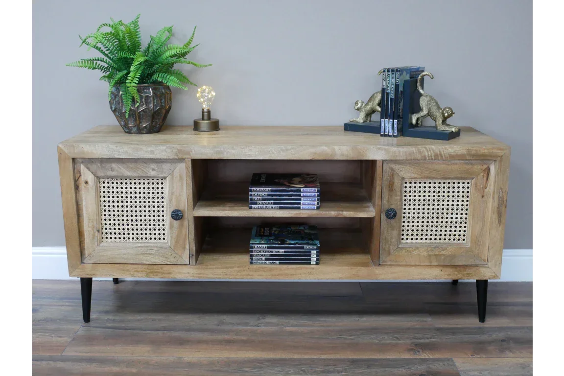 Wooden TV unit with rattan cabinet doors, open shelving, black legs, and decor accents on top