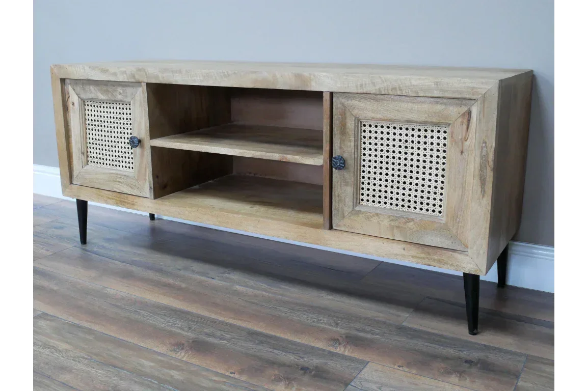 Wooden TV unit with rattan doors, open shelving and black metal legs on wood flooring