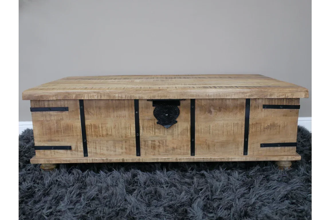 Rustic wooden storage chest with black iron hardware on grey shaggy rug