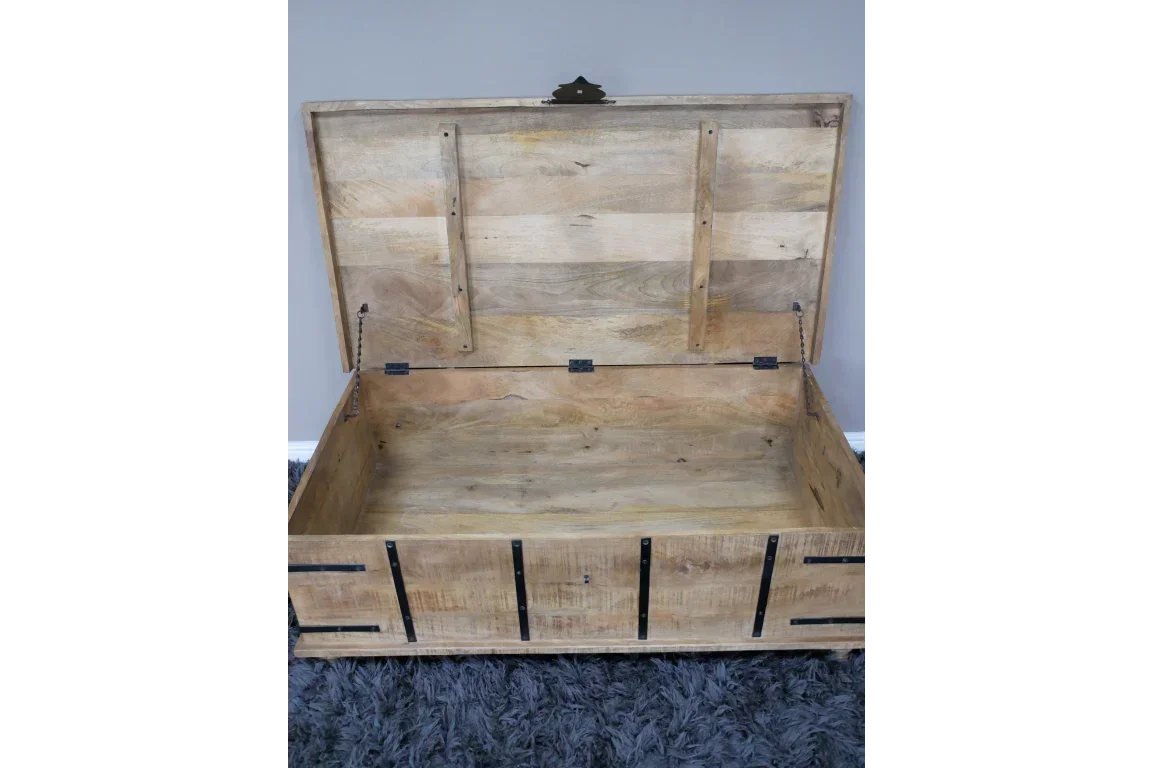 Open wooden storage chest with metal hinges on grey rug