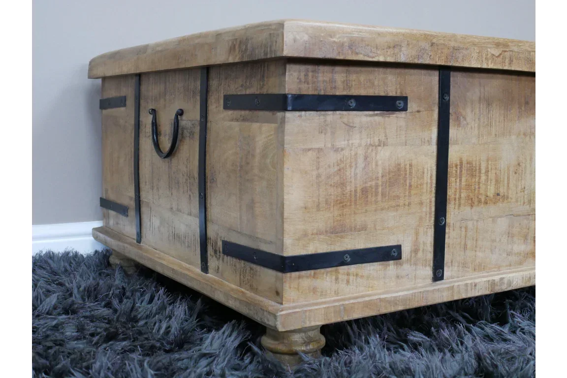 Solid wood storage chest with black metal handles and brackets on grey shaggy rug