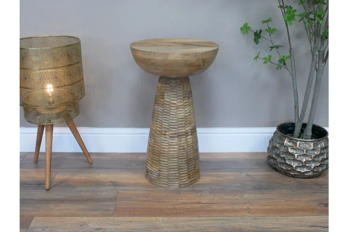 Hand carved wooden side table with textured conical base on wooden floor