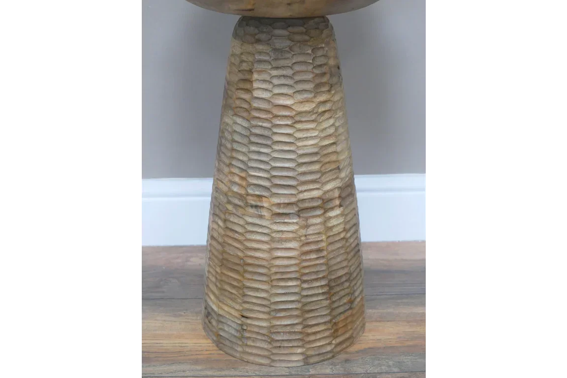 Textured wooden side table base with carved oval pattern on wood floor