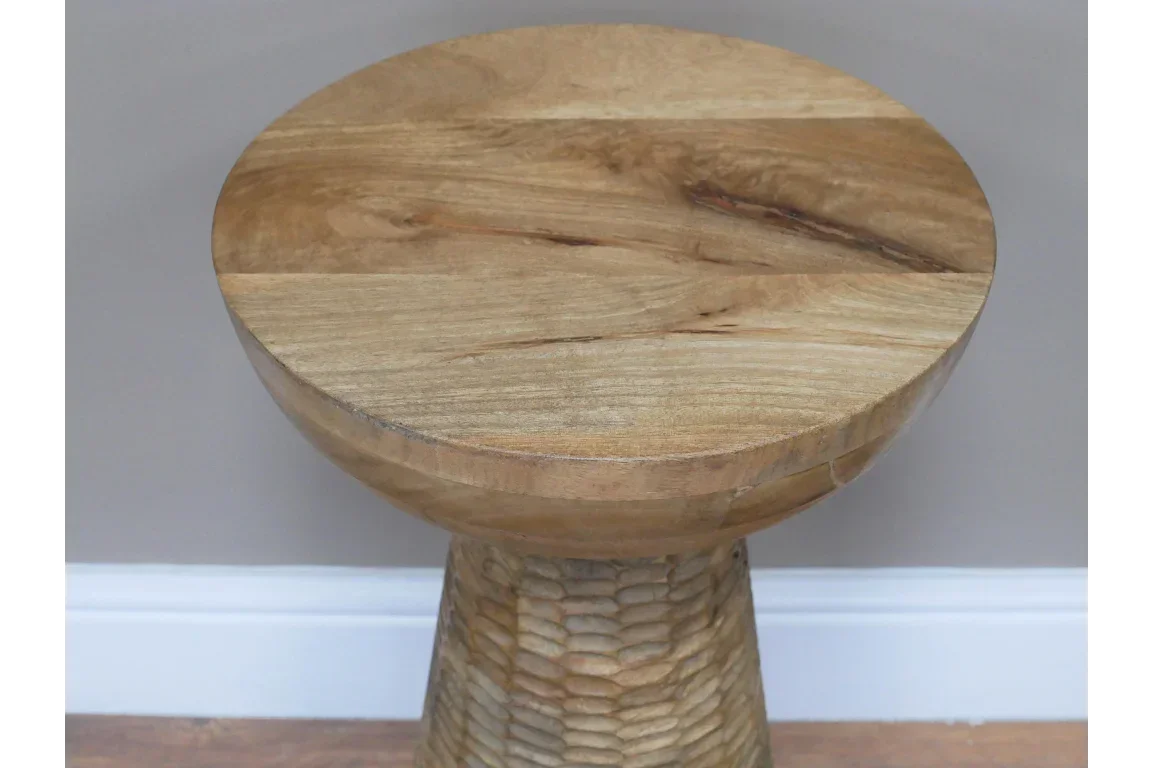 Round wooden side table with textured pedestal base on hardwood floor