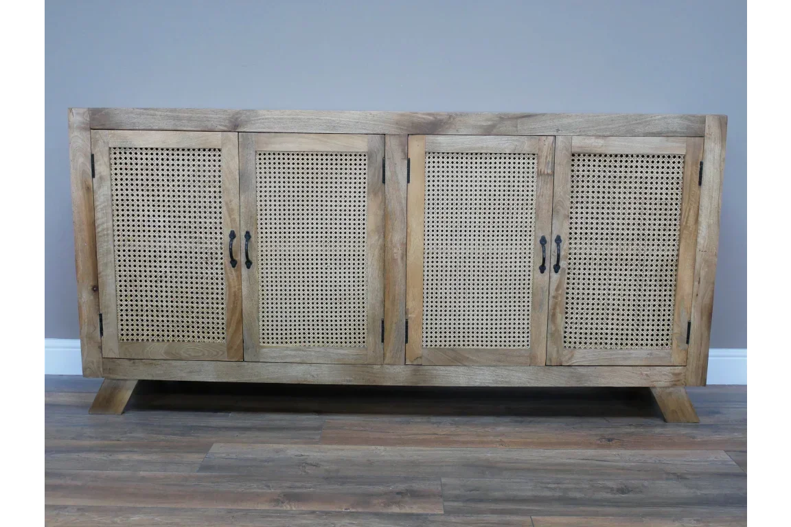 Natural wood sideboard with four rattan doors and black metal handles on wooden floor