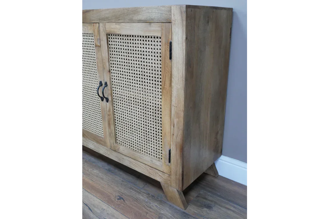 Natural wood sideboard with cane panel doors and black metal handles on wooden floor