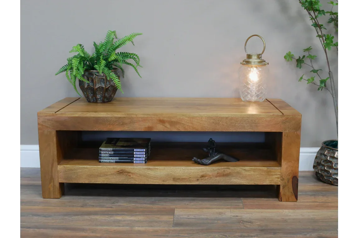 Solid wood coffee table with lower shelf, potted plant, books, and glass lantern top