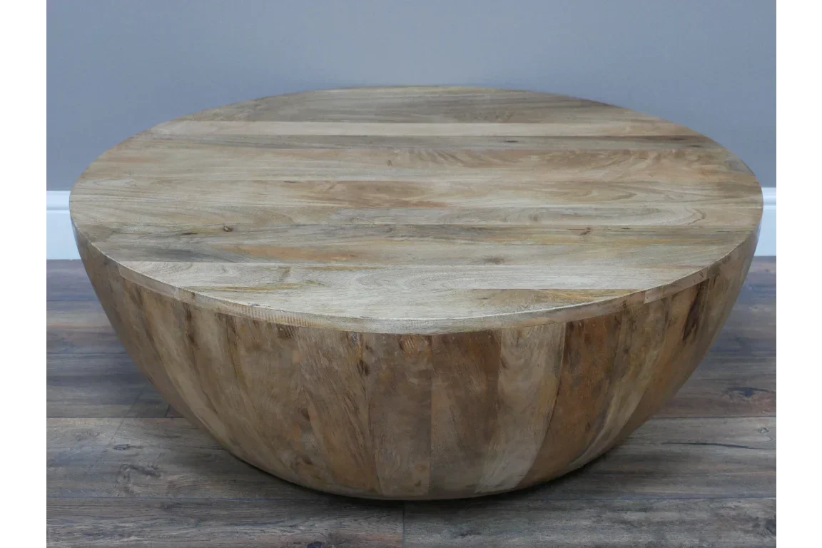 Round solid wood coffee table with natural finish on wooden floor