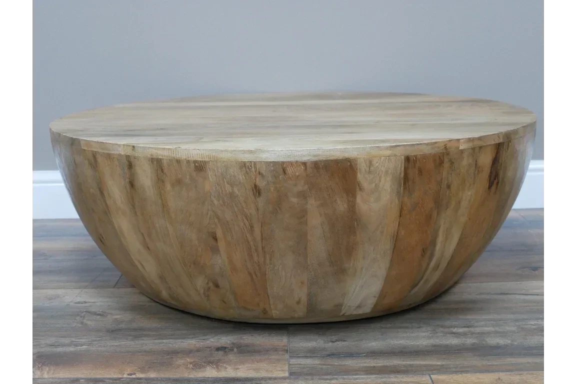 Round solid wood coffee table with natural finish on wooden floor
