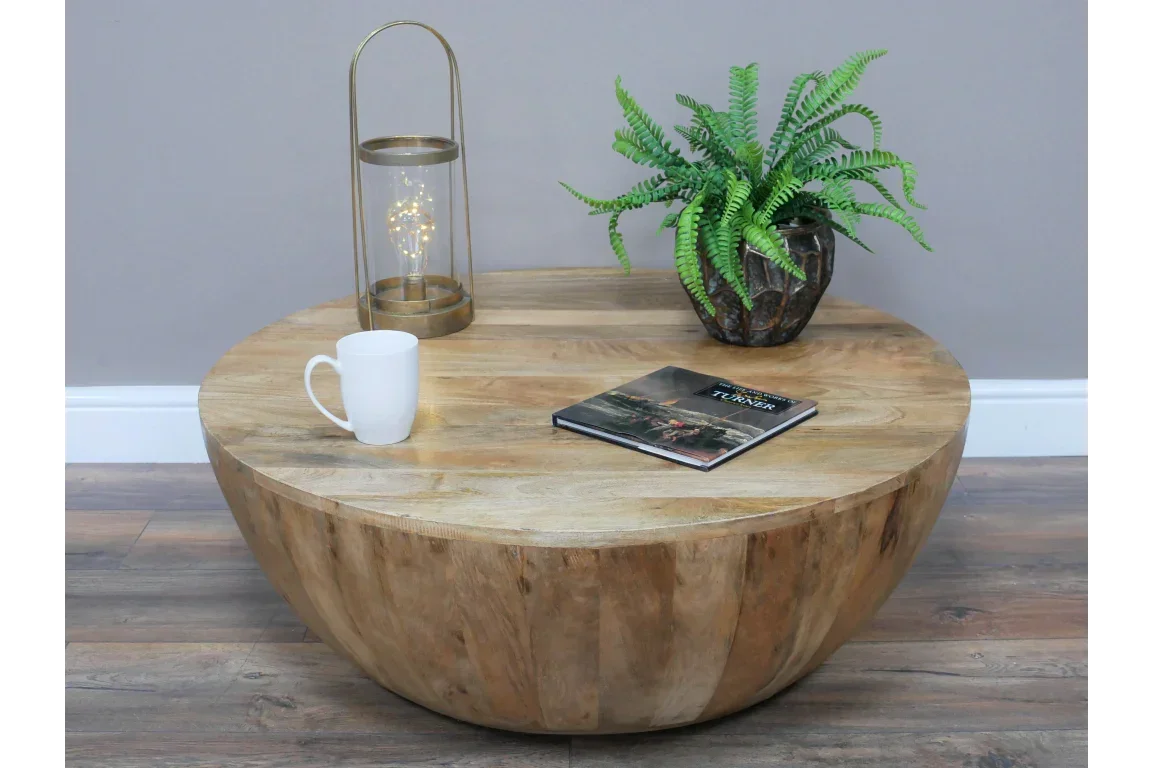 Round wooden coffee table with lantern, plant, book and white mug on wood floor