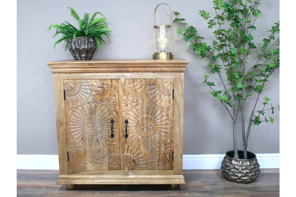 Carved wood sideboard cabinet with floral patterns, black handles, styled with plant decor