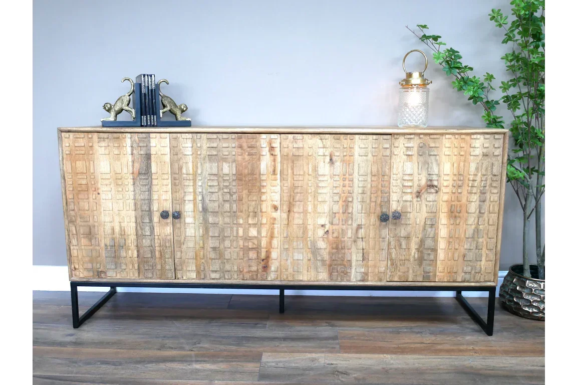 Carved wood sideboard with metal legs and textured cabinet doors on wood flooring