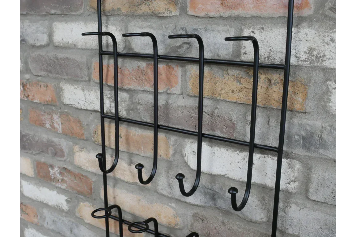 Black metal wall mounted coat rack with hooks against exposed brick wall