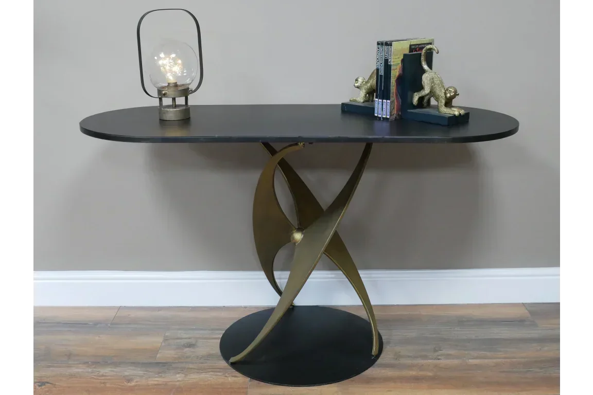 Modern console table with black top, gold sculptural base, lamp and decorative bookends