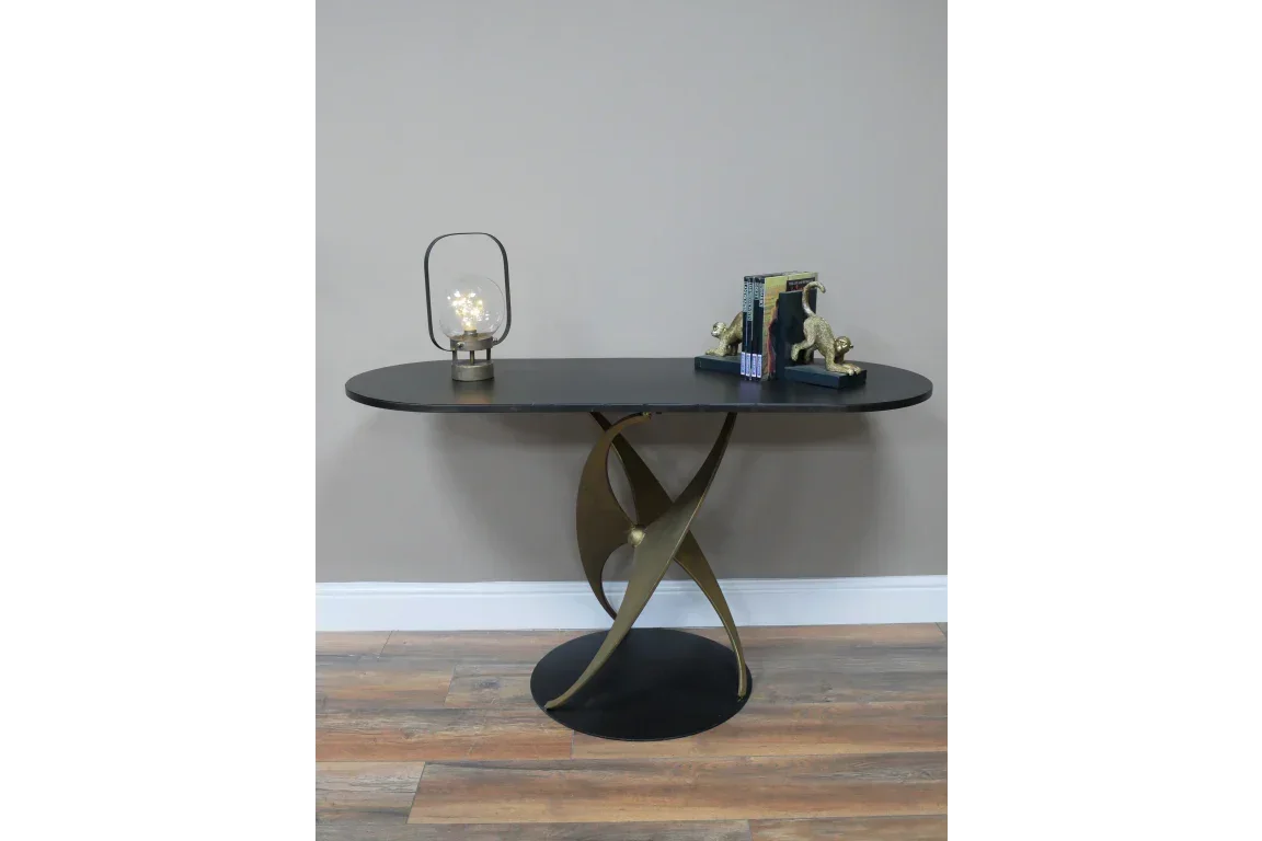 Black and gold console table with curved metal base, lamp and decorative bookends