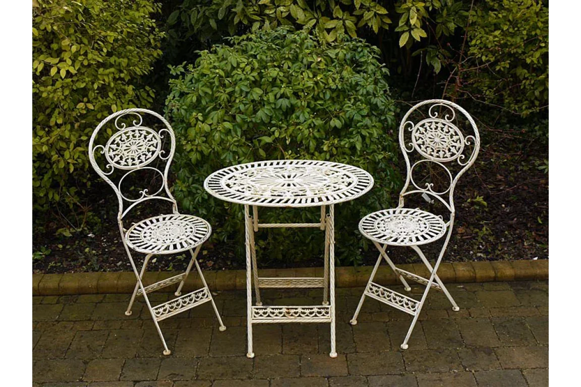 White metal bistro set with round table and two chairs on garden patio
