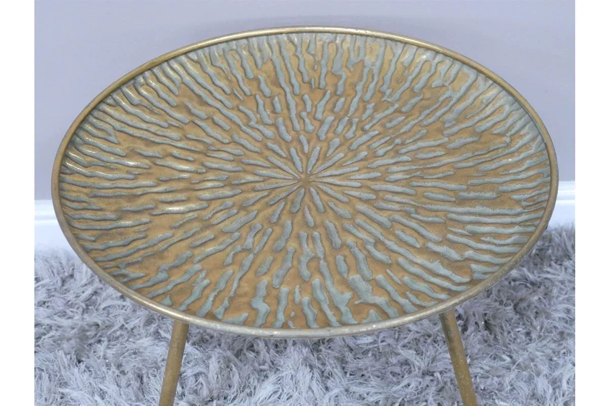 Round metal side table with gold textured top on grey rug