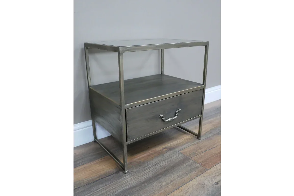 Metal frame bedside table with glass top, open shelf, and single drawer on wood floor