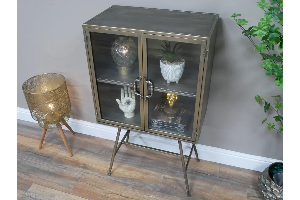 Glass display cabinet with metallic frame and legs, styled with ornaments and books