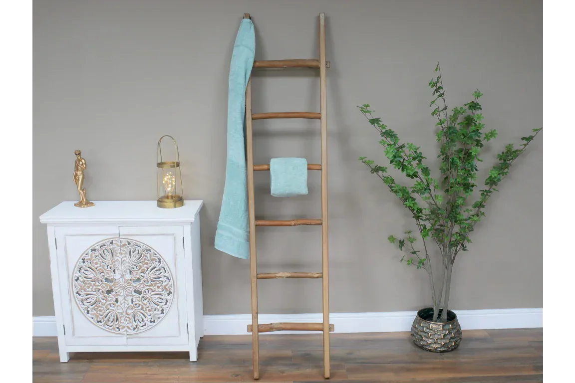 Bamboo towel ladder with aqua towels beside white cabinet and artificial potted plant
