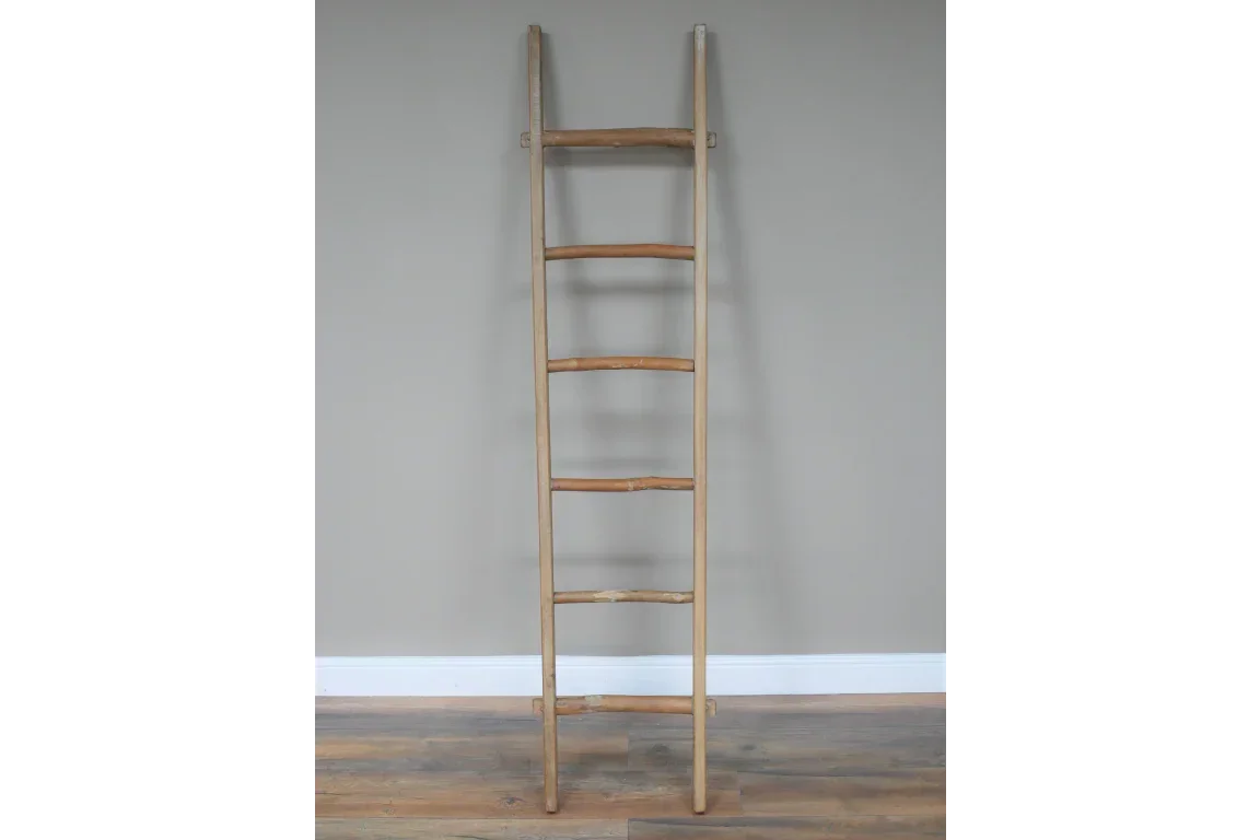 Natural bamboo ladder shelf with five rungs against a grey wall on wood flooring